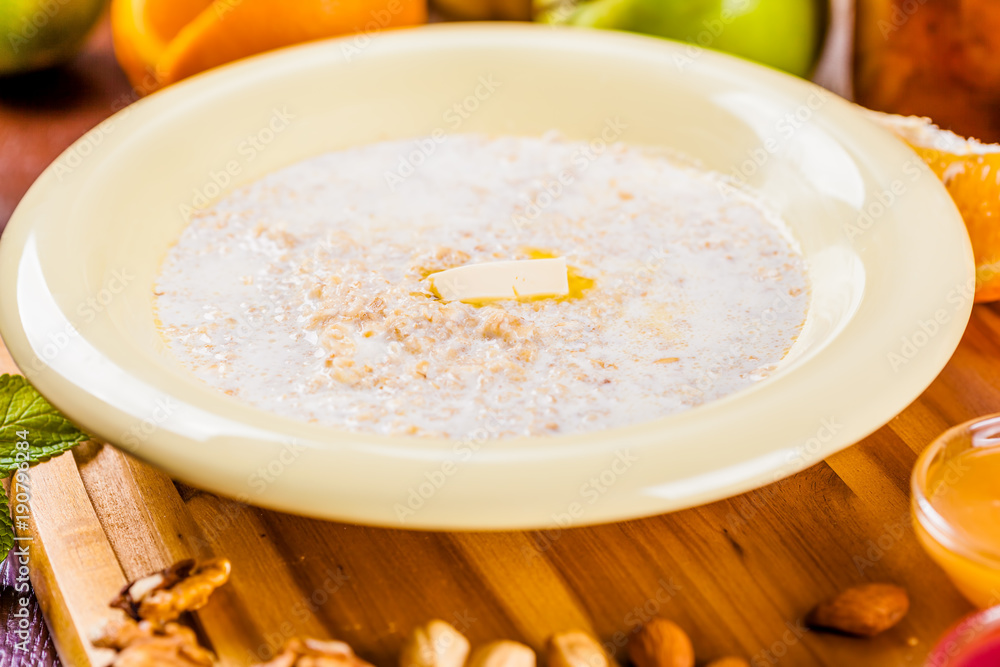 Oatmeal porridge with nuts, jam and fruits on wooden board Oatmeal porridge with nuts, jam and fruits on wooden board
