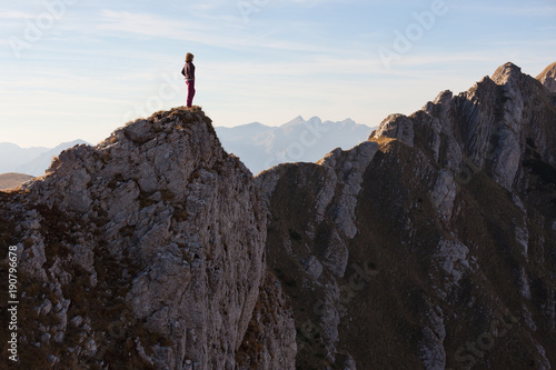 Woman high on cliff looking out at view of the deep canyon