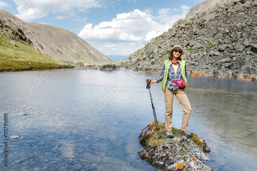 girl hiker standing on a rock and looking at the lake in Altai mountains