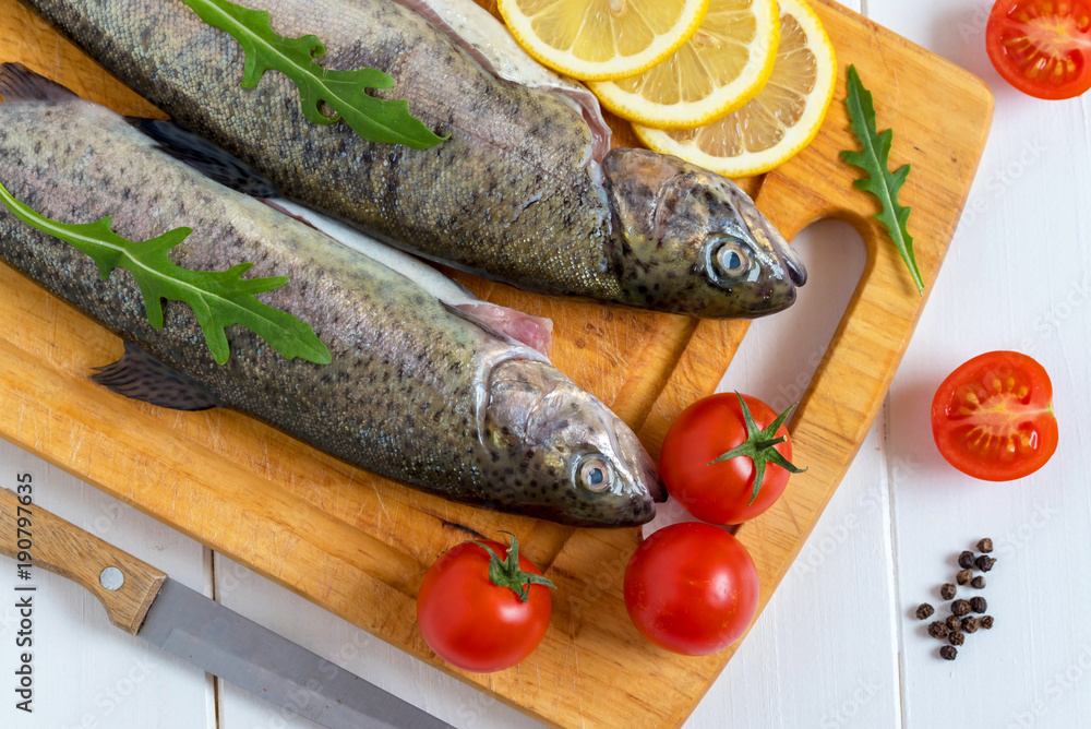 Fresh raw trout fish and food ingredients on wooden board. Fresh raw trout fish and food ingredients on wooden board.