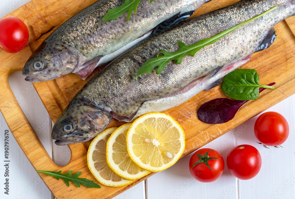 Fresh raw trout fish and food ingredients on wooden board. Fresh raw trout fish and food ingredients on wooden board.
