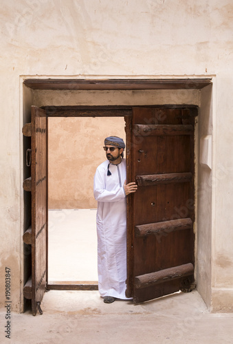 arab man in traditional omani outfit in an old castle photo