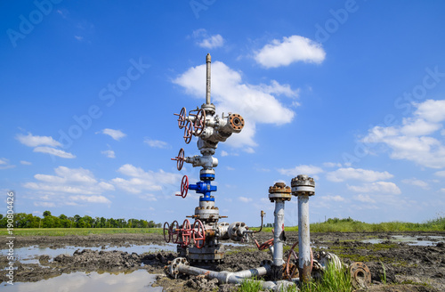 Oil well after repair in mud and puddles. Oil well wellhead equipment. Hand valve with handwheel for opening and closing the flow line photo