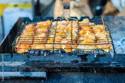 The process of cooking shish kebab on a metal grill in the open air.Grilling shashlik on barbecue grill. Marinated meat. photo