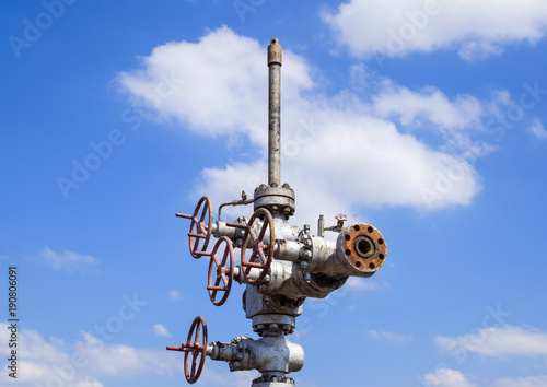 Oil well after repair in mud and puddles. Oil well wellhead equipment. Hand valve with handwheel for opening and closing the flow line photo