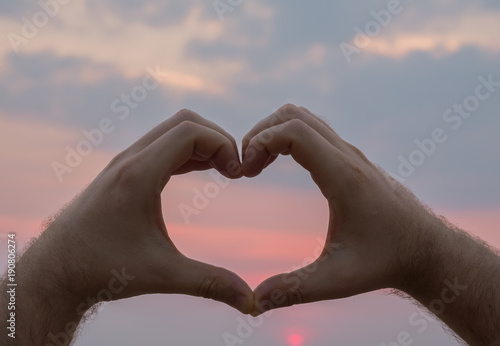 Man hand heart shape in sunset on the beach. Love concept