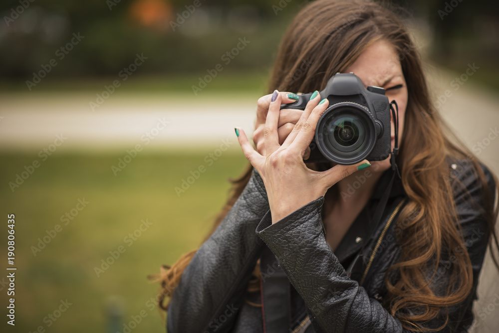 Young professional or amateur photographer taking a picture with her dslr camera
