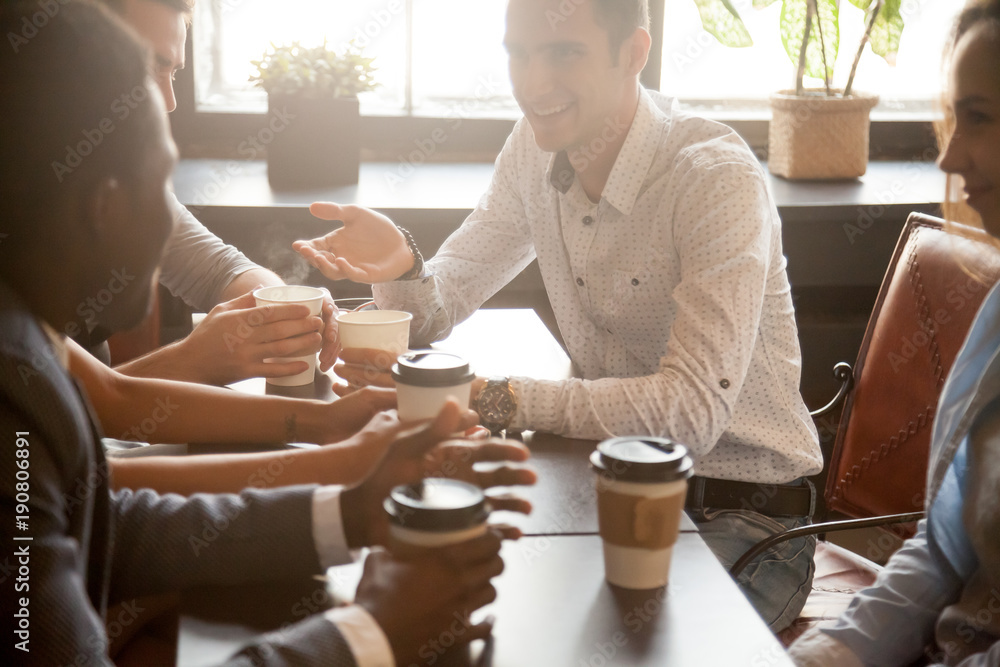 Multi ethnic group of happy friends drinking coffee in paper cups