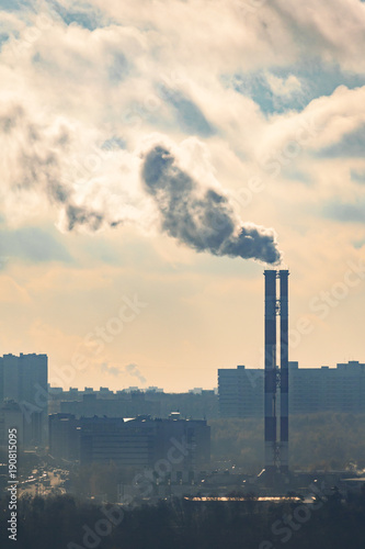 Steaming chimneys on a background of city houses and a cloudy sky