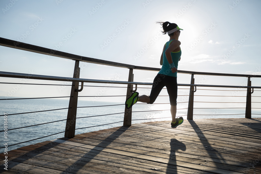 Sporty fitness female runner running on seaside boardwalk during sunrise Sporty fitness female runner running on seaside boardwalk during sunrise