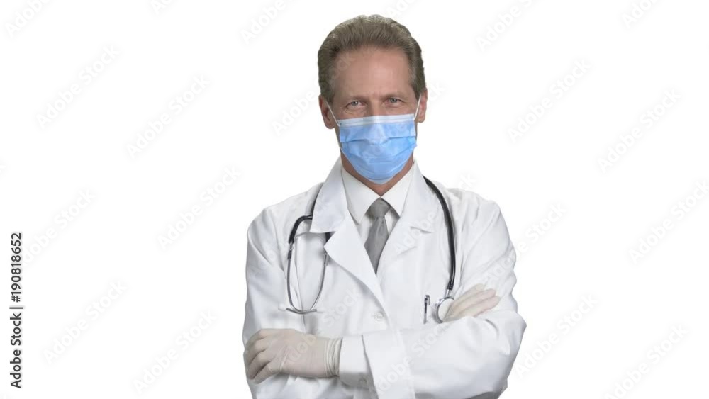 Front view confident mature doctor in mask. Middle aged physician with crossed arms in medical coat, white isolated background. Front view confident mature doctor in mask. Middle aged physician with crossed arms in medical coat, white isolated background.