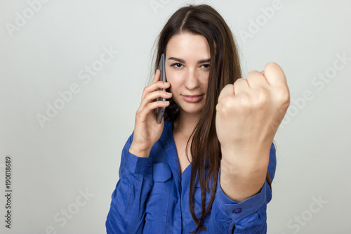 Woman using a cell phone shows a fist