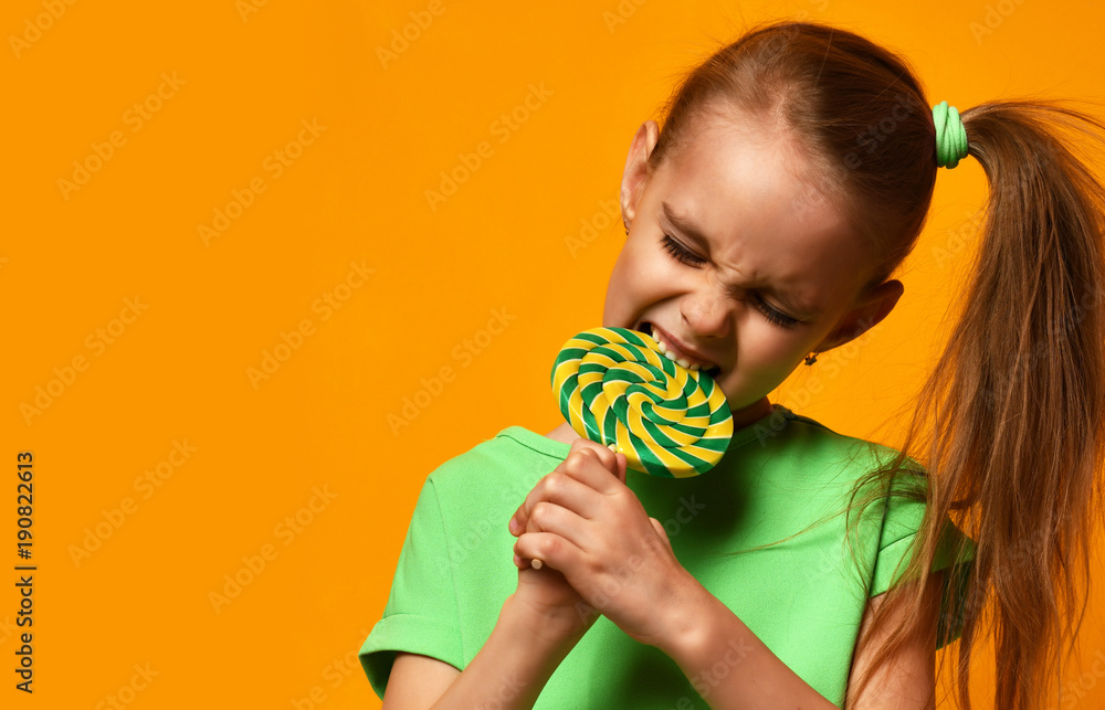Happy young little child girl kid bite sweet lollypop candy Happy young little child girl kid bite sweet lollypop candy