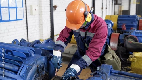 Worker repairing pipelinein pump station at oil production department