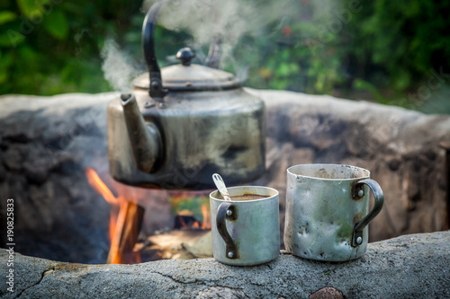 Hot and aromatic coffee with kettle on campfire