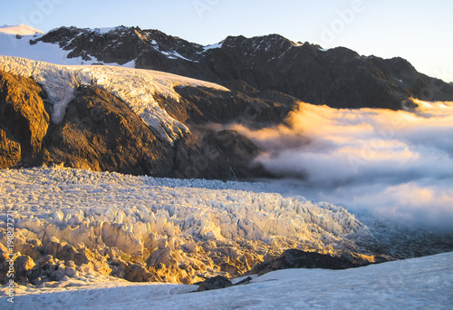 A layer of clouds blankets the Fox Glacier during sunset on the south island of New Zealand.
