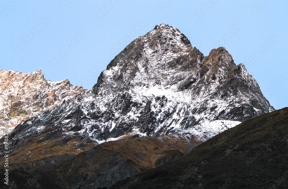 A jagged rocky peak sprinkled with snow in the Matukituki Valley, Mt. Aspiring National Park, south island of New Zealand.