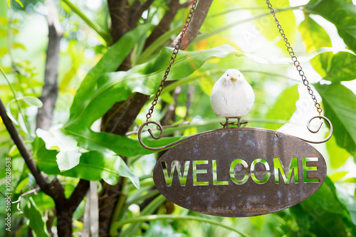 welcome sign with Bird statue and bokeh background of the house photo