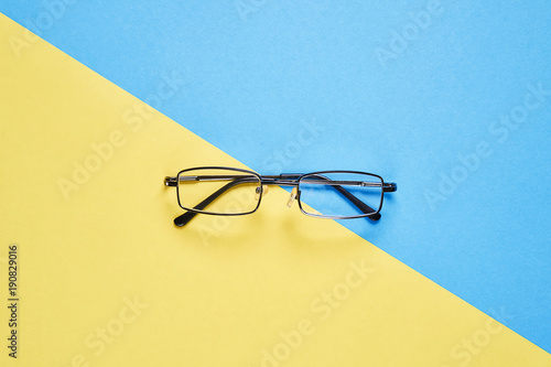 Eyewear placed on a pastel yellow and blue background divides the halves.