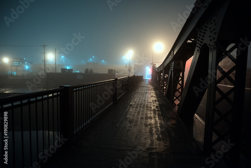 Dramatic industrial vintage river bridge scenery at night with illuminating fog in Chicago. © Bruno Passigatti