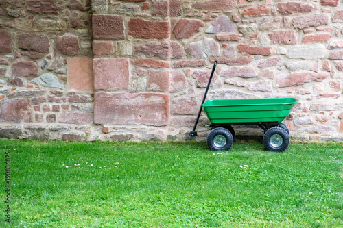 A green garden pushcart, wheelbarrow on the green grass field.