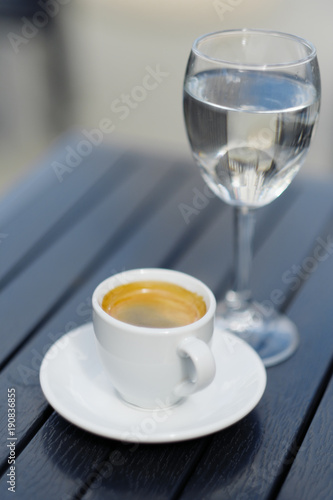 White cup of coffee and glass of water place on wood table
