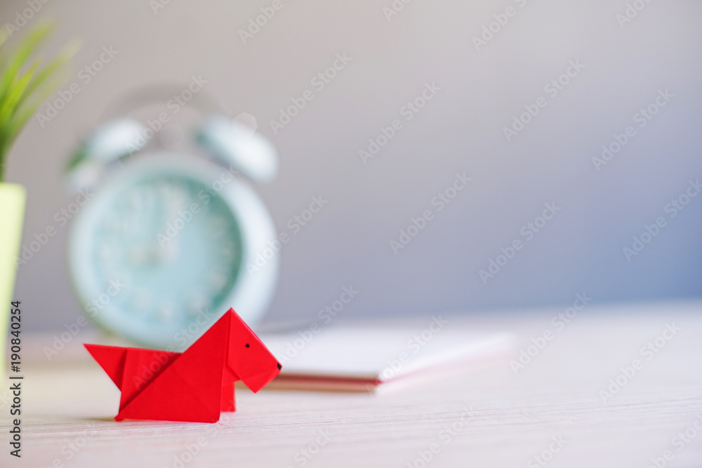 Red dog origami with blur alarm clock in the background.Chinese new year concept.Lunar year of dog.