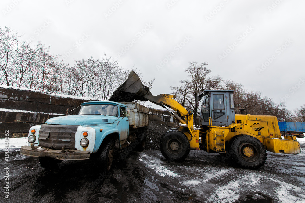 The tractor loads coal into the truck. The tractor loads coal into the truck.