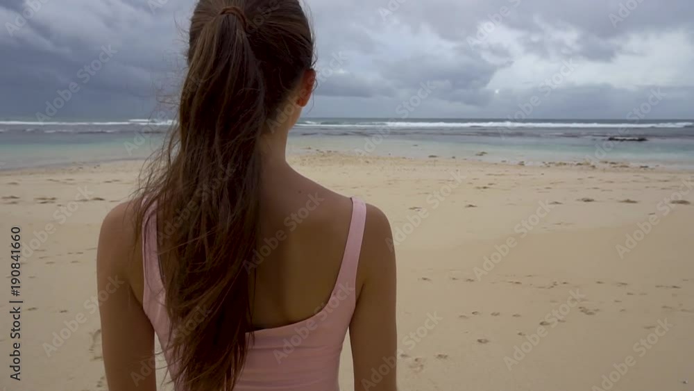 Woman looks on sea, enjoying beach at sunrise Woman looks on sea, enjoying beach at sunrise