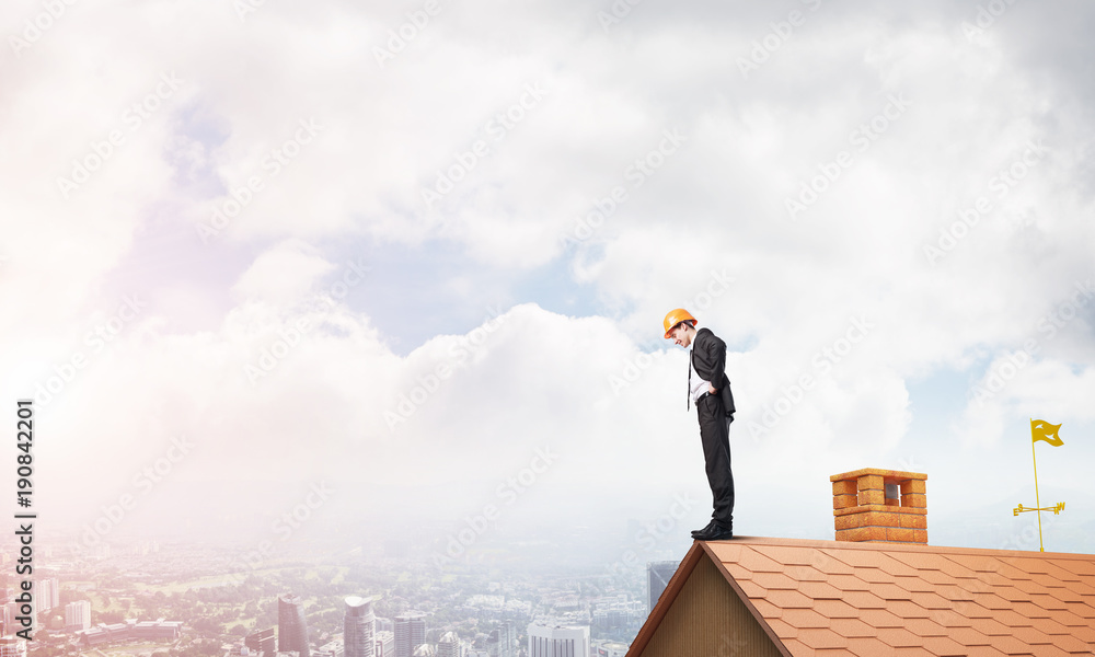 Businessman looking down from roof and modern cityscape at background. Mixed media Businessman looking down from roof and modern cityscape at background. Mixed media