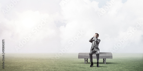 Young man in summer park on bench do not want to see anything