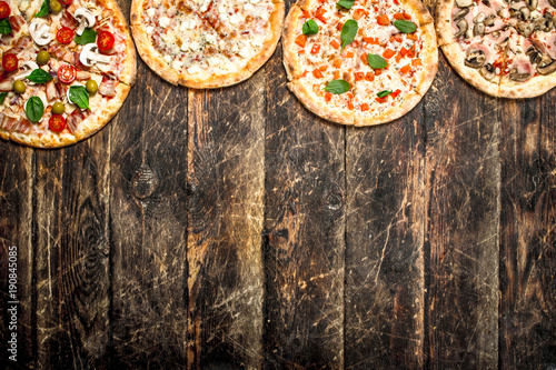variety of pizzas. On wooden background