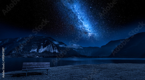 Wooden bench and lake mountain between at night with stars