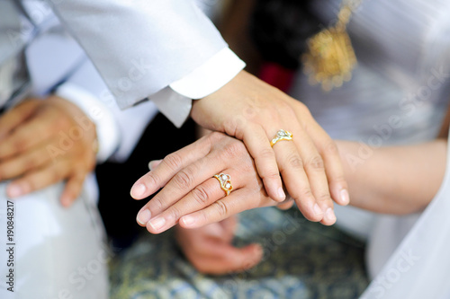 man and woman holding hands with wedding ring