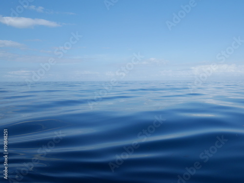 Fototapeta Naklejka Na Ścianę i Meble -  Blue ocean water, horizon line, water connects with the sky, blue sky, white clouds, calm water, calm ocean, Pacific Ocean, Indian ocean, beautiful scenery, the depth of the sea