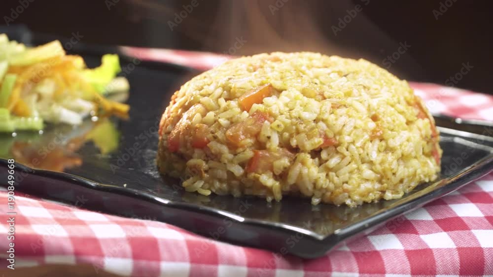 Delicious Ramadan Food steamy Rice Pilaf with Grated Tomato and Hot Pepper paste sauce serving with lettuce, and grated carrot on black plate rotating shot. Delicious Ramadan Food steamy Rice Pilaf with Grated Tomato and Hot Pepper paste sauce serving with lettuce, and grated carrot on black plate rotating shot.