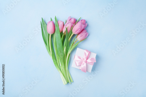Spring tulip flowers and gift box on blue pastel table top view. Greeting card for Birthday, Womans or Mothers Day. Flat lay.