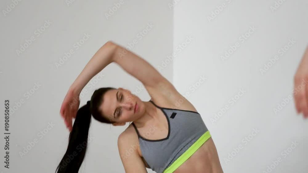 Beautiful girls perform slopes in the side on their knees, exercises for Pilates. Smooth movements of hands while practicing yoga. Close-up camera moves from one girl to another Beautiful girls perform slopes in the side on their knees, exercises for Pilates. Smooth movements of hands while practicing yoga. Close-up camera moves from one girl to another