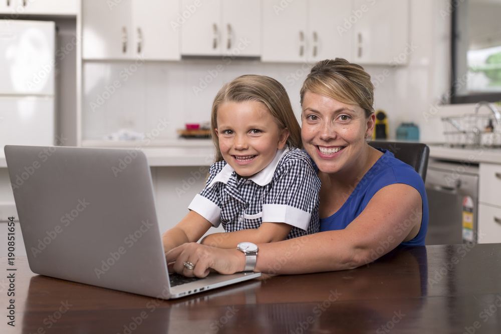 blond mother woman together with her young beautiful and sweet little girl 6 to 8 years old sitting at home kitchen enjoying with laptop computer blond mother woman together with her young beautiful and sweet little girl 6 to 8 years old sitting at home kitchen enjoying with laptop computer