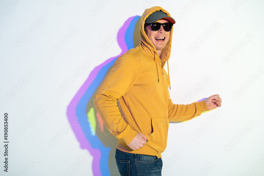 Fototapeta premium Portrait of laughing male standing with multicolored shadow gesticulating hands. Entertainment concept