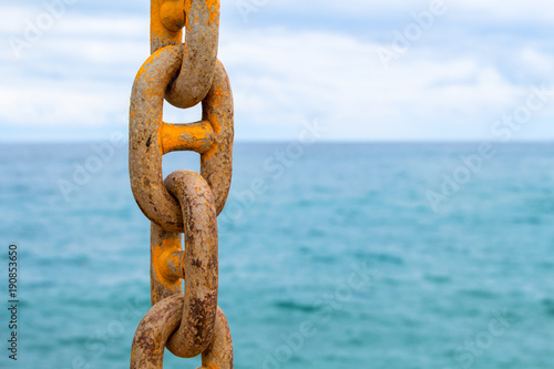 Chain and blue sea. Yellow mooring chain of cargo ship. Commercial shipment by sea.