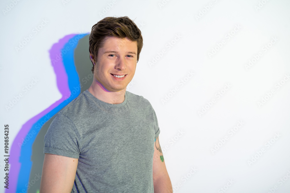 Obraz premium Portrait of beaming man standing with multicolored shadow. Positive concept. Copy space