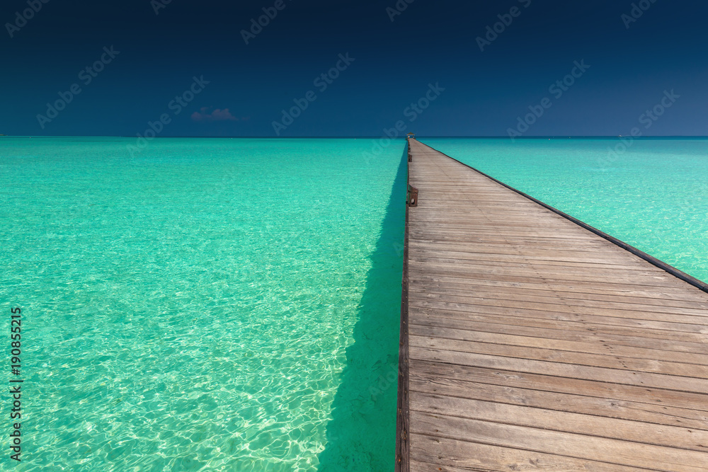 Wooden long jetty over lagoon with amazing clean azure water
