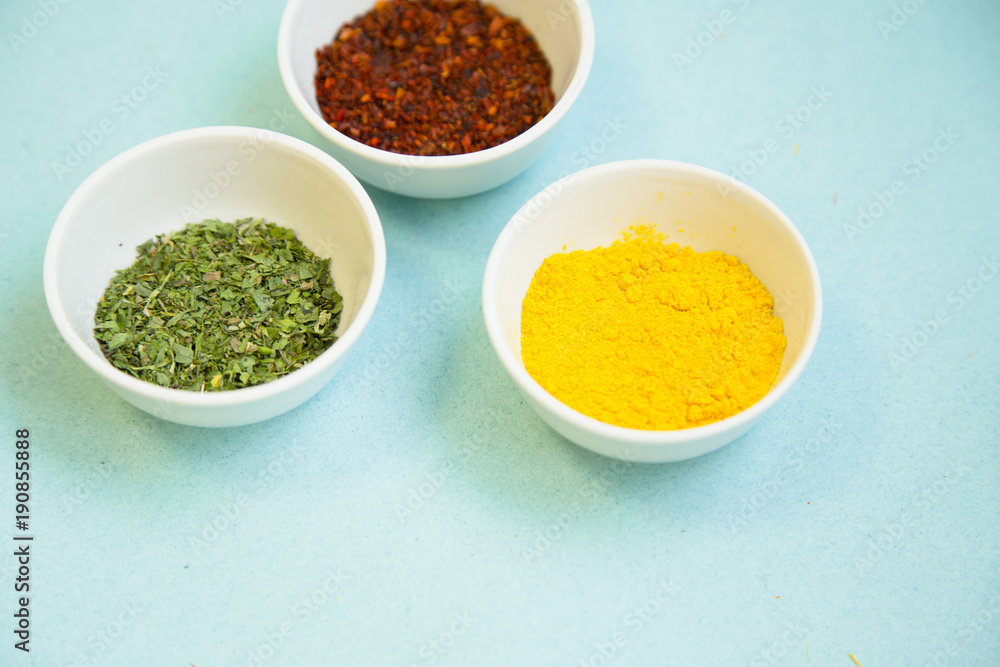 Plastic cups with dry spices and fresh herbs on a blue background with copy space, top view, close up Plastic cups with dry spices and fresh herbs on a blue background with copy space, top view, close up