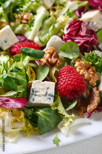 Green salad with blue cheese , raspberry and nuts.