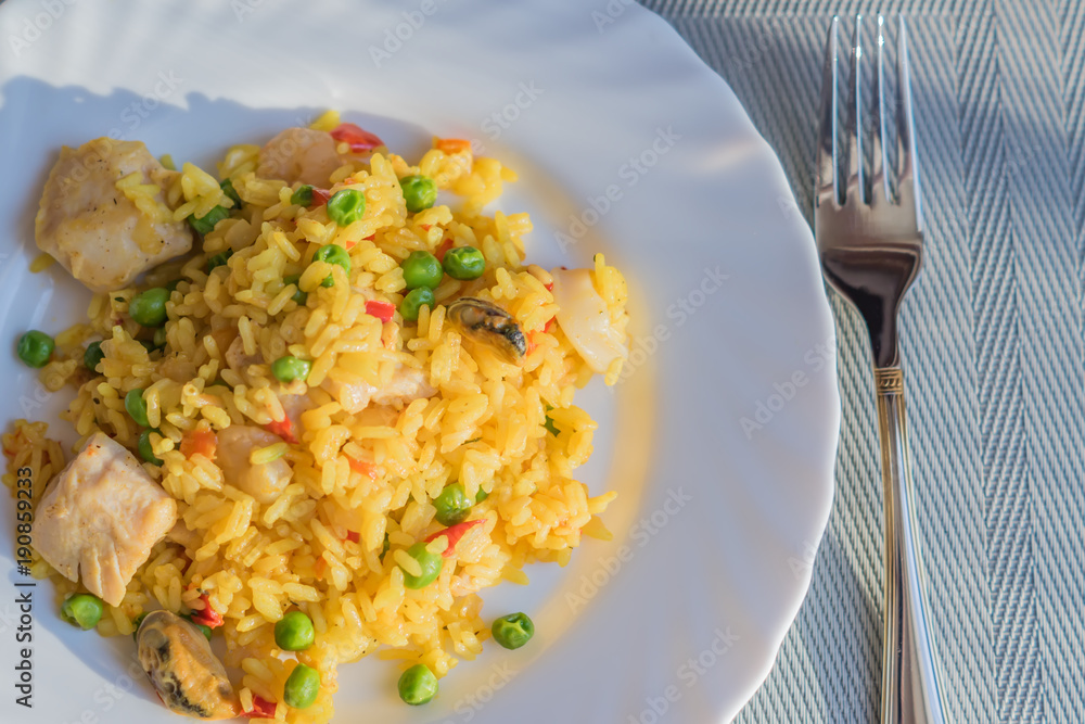 paella with chicken and seafood on white plate. Spanish dish served on table  Stock Photo | Adobe Stock