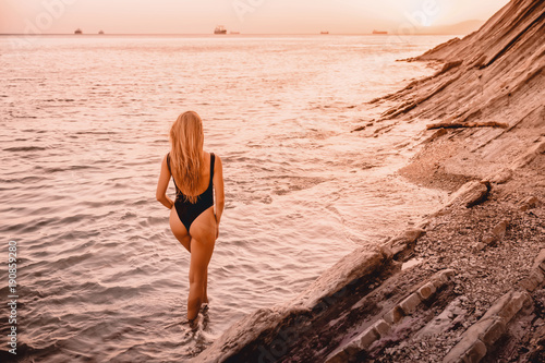 Blonde woman in swimwear bikini with summer sunset.