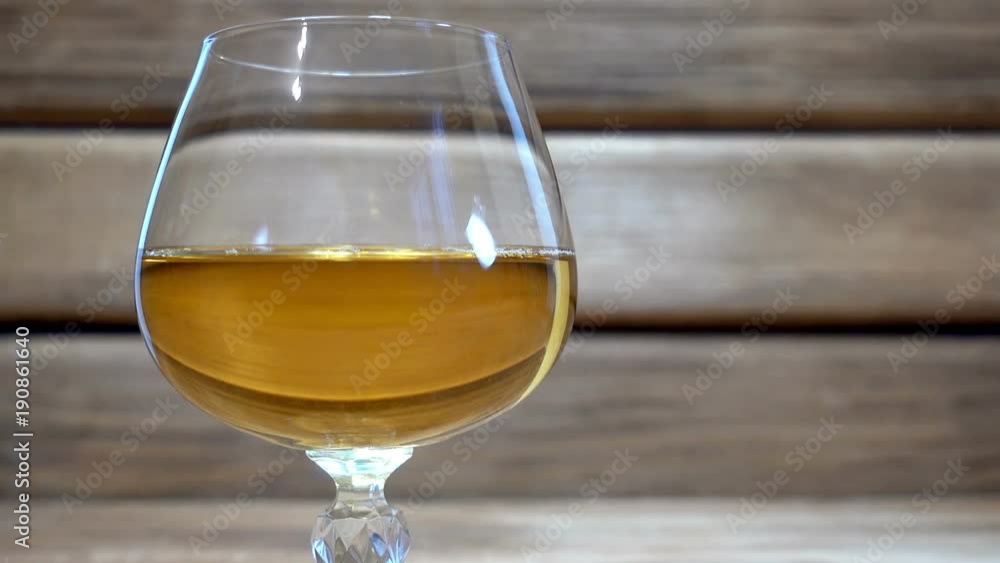 Close-up of a glass of cognac on a wooden background. HD video clip Close-up of a glass of cognac on a wooden background. HD video clip