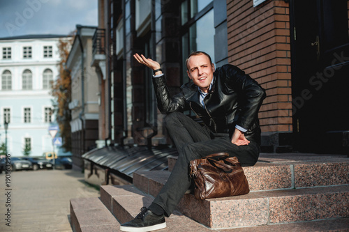 a young man in a leather jacket and with a bag 