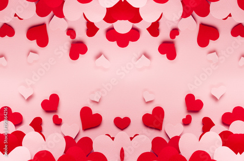Red and pink paper hearts different size on pink background. Valentine day backdrop.